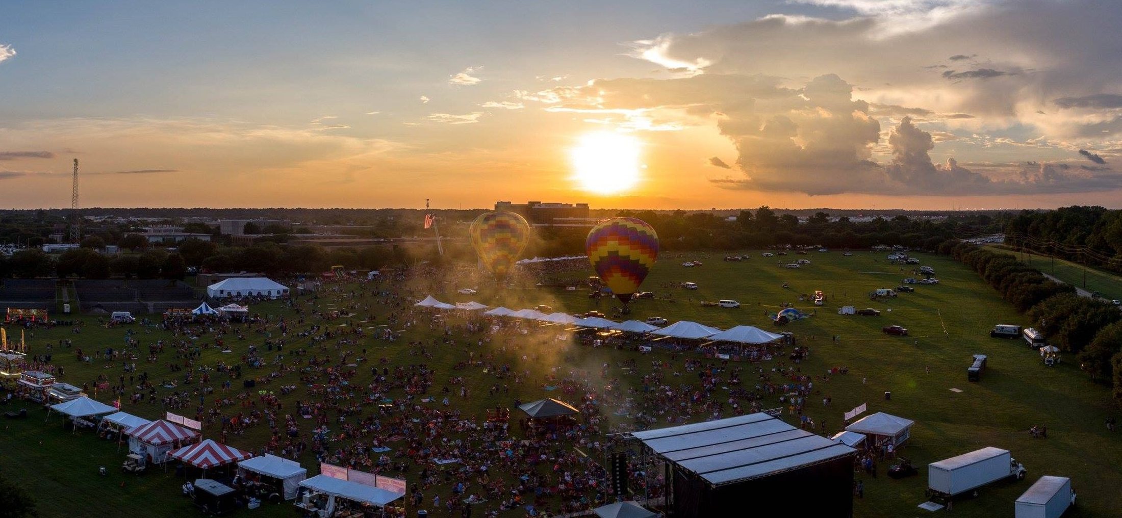 Aerial view of a festival at sunset with Encore tents, staging, and equipment serving thousands of guests